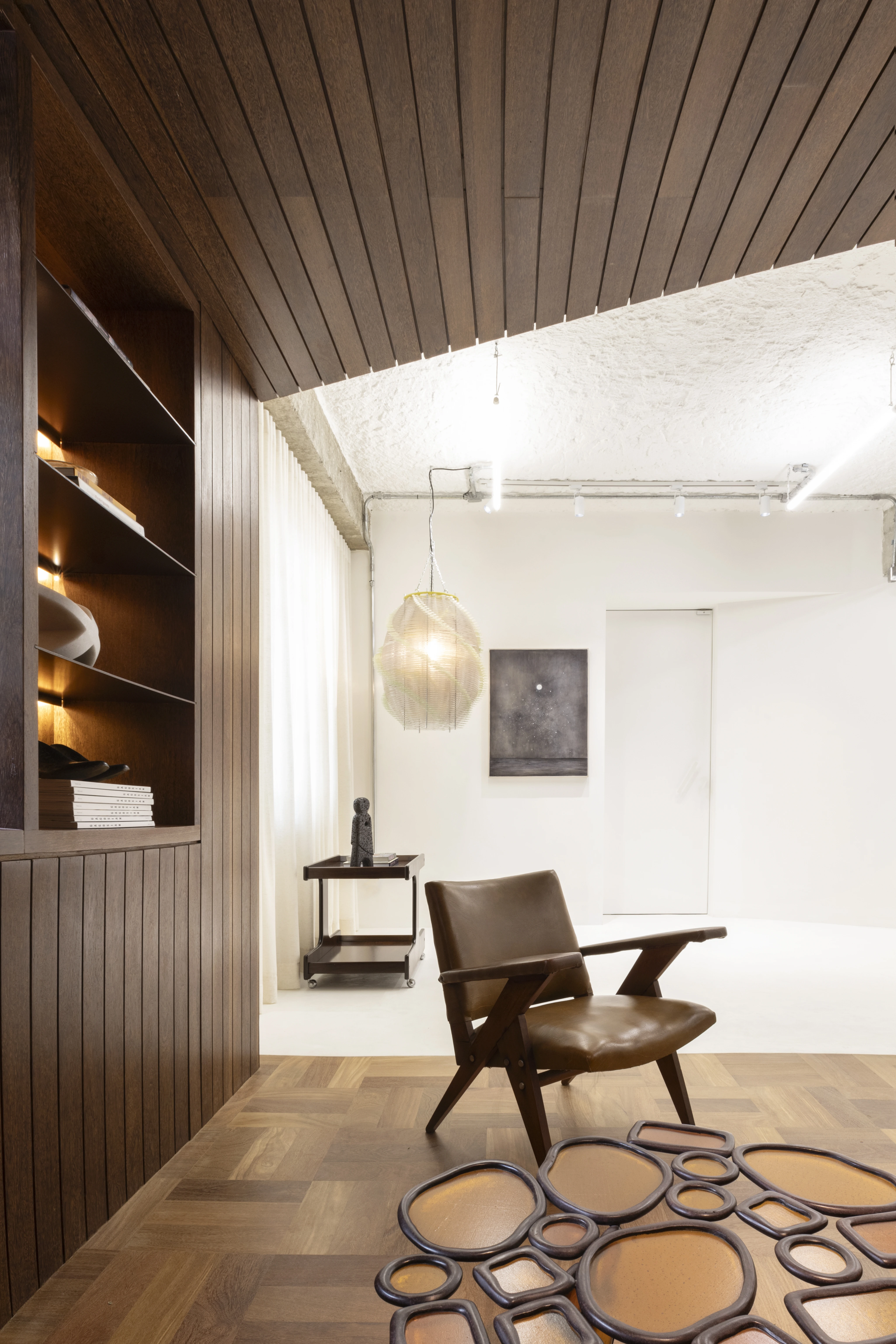 Living room with wooden walls with lights and a white backdrop, and modern furniture